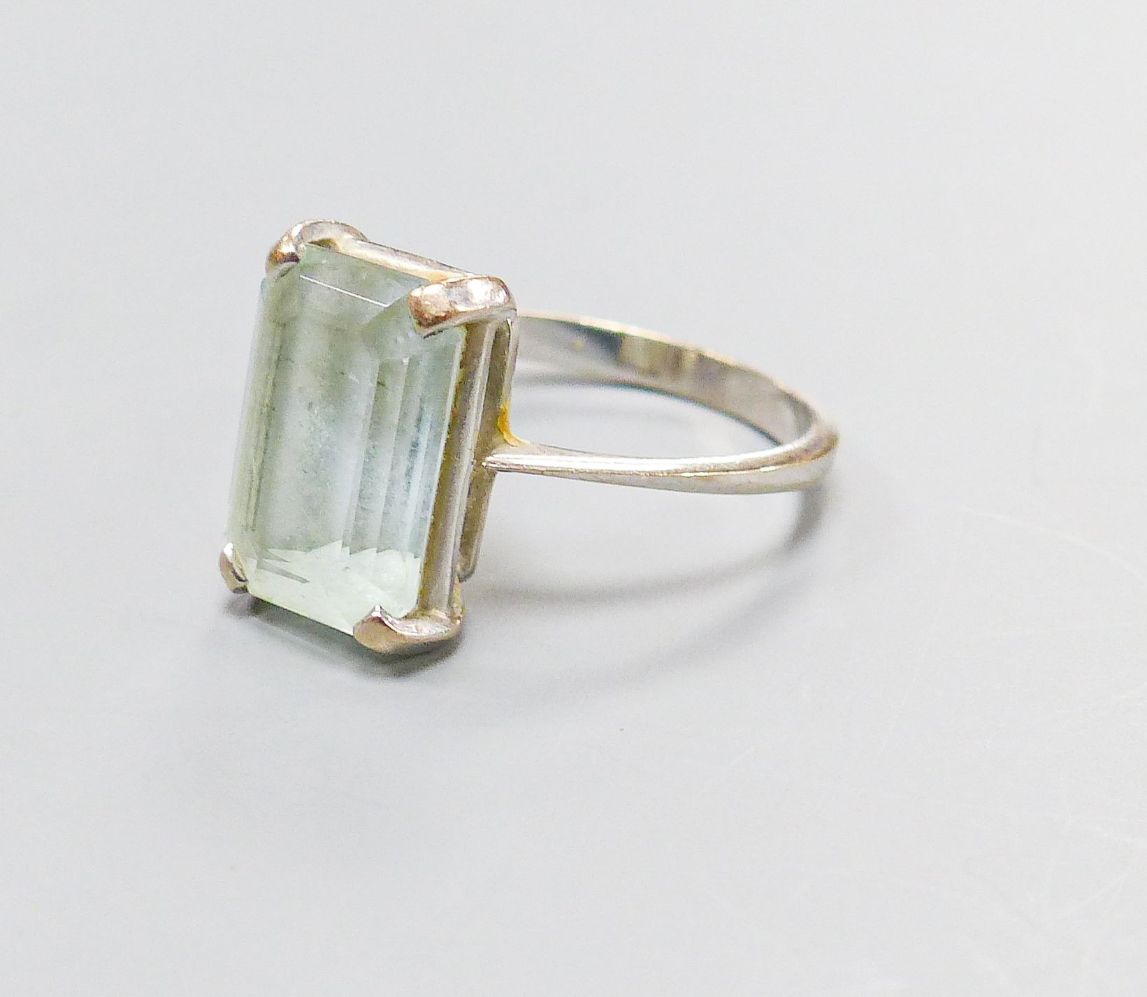 A 750 white metal and emerald cut aquamarine set ring, size O, gross weight 4.6 grams.